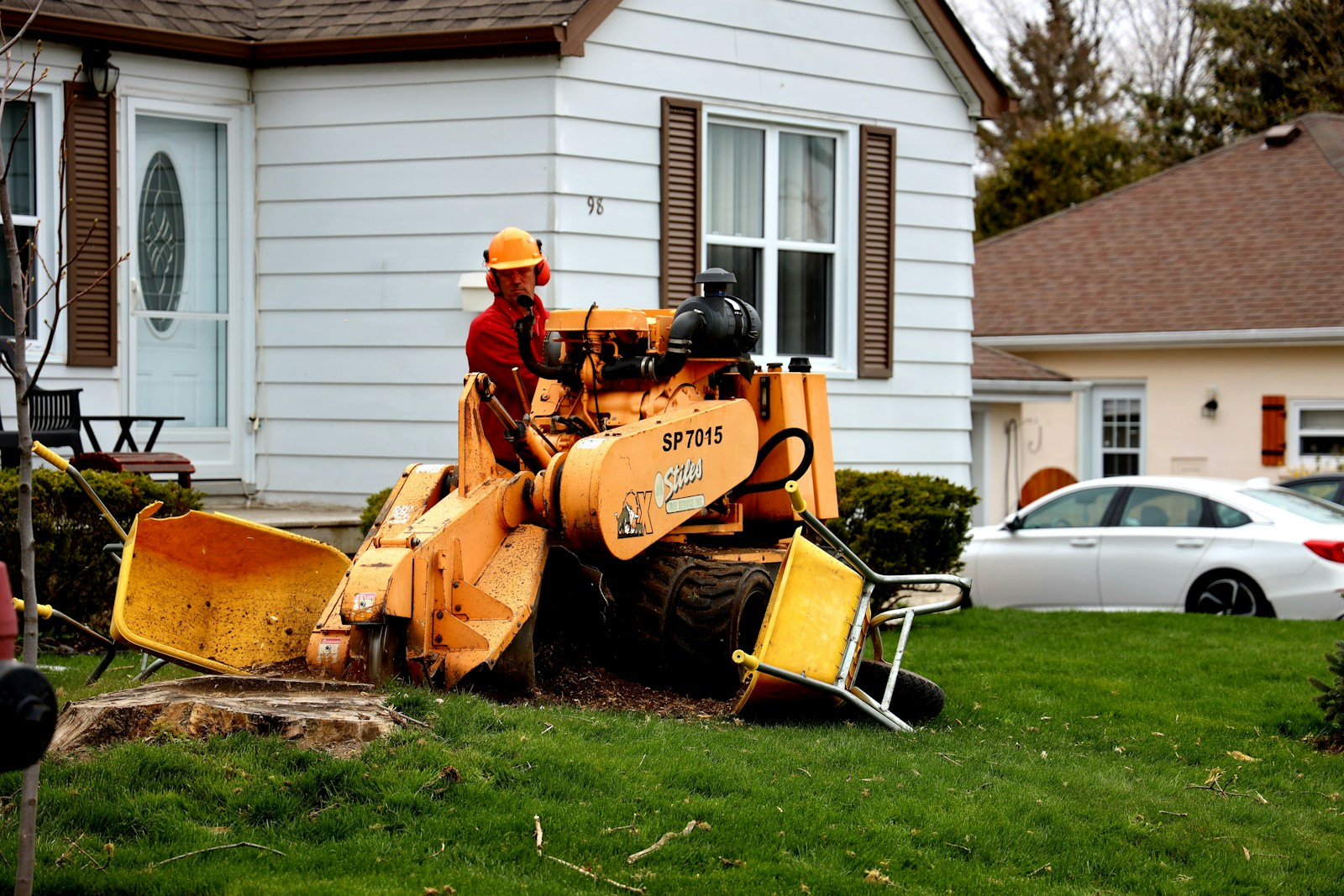 man in orange jacket sitting on yellow and black tractor
